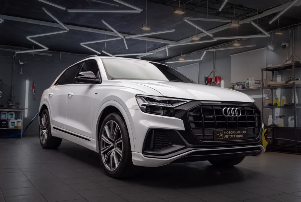 Белый Audi в рабочем боксе автостудии, вид спереди сбоку
